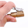 A hand holds a brass tire inflator quick-connect adapter with a clip-on lock mechanism.