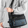 A man wearing a light gray jacket holds a navy blue nylon crossbody sling bag.
