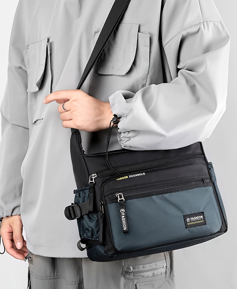 A man wearing a light gray jacket holds a navy blue nylon crossbody sling bag.