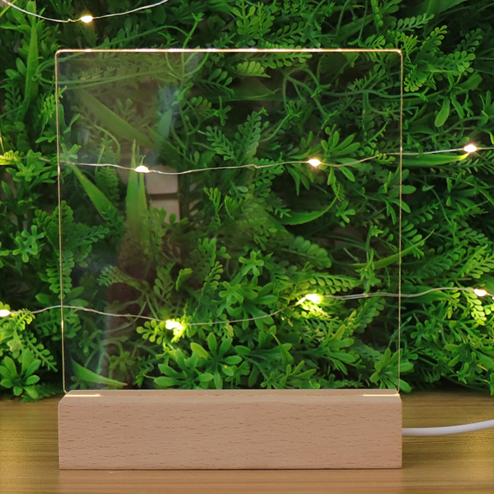 Illuminated acrylic guitar pick holder with a wooden base set against a green foliage background