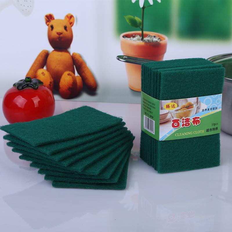 A stack of green microfiber cleaning cloths next to a small stuffed lion and a red tomato.
