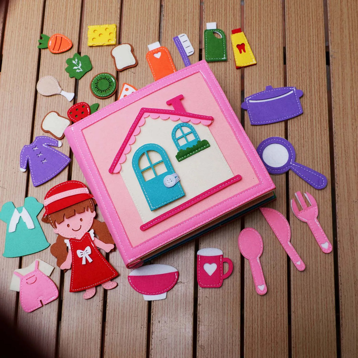 A felt activity busy book for toddlers featuring various shapes and tools like a house, magnifying glass, and cutlery.