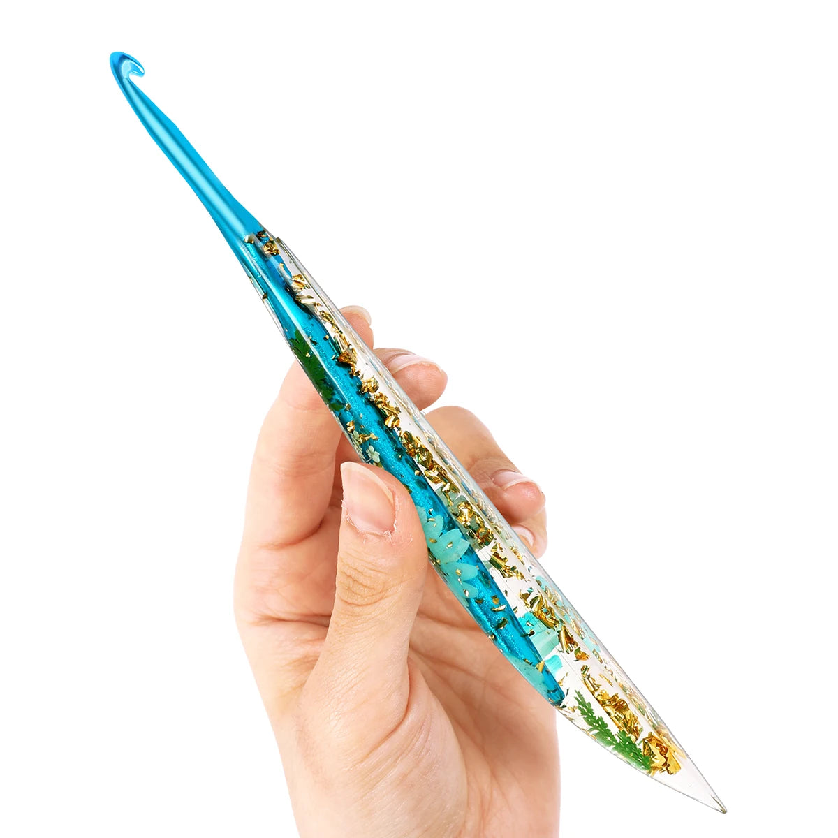 A hand holds a blue epoxy resin floral-patterned crochet hook set with a pointed tip.