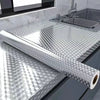 Roll of self-adhesive aluminum foil used as a kitchen backsplash protector next to a stainless steel sink.