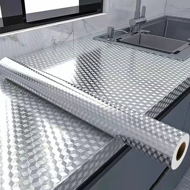 Roll of self-adhesive aluminum foil used as a kitchen backsplash protector next to a stainless steel sink.