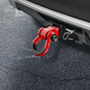 A red heavy-duty shackle with a D-ring and trailer pin is attached to a vehicle's hitch receiver.