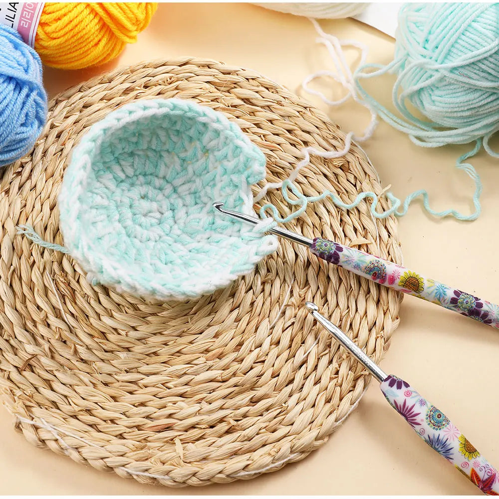 A crochet hook set with sunflower designs is shown next to a light blue crocheted bowl on a woven mat.