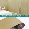 Roll of light wood grain self-adhesive wallpaper in a natural beige color.