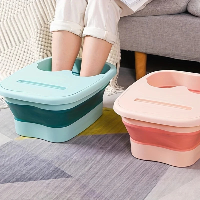 Two collapsible foot spa buckets in teal and pink resting on a gray rug next to a person's legs.
