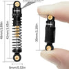 A black anodized aluminum shock absorber with a gold-colored coil spring shown next to a human finger for scale.