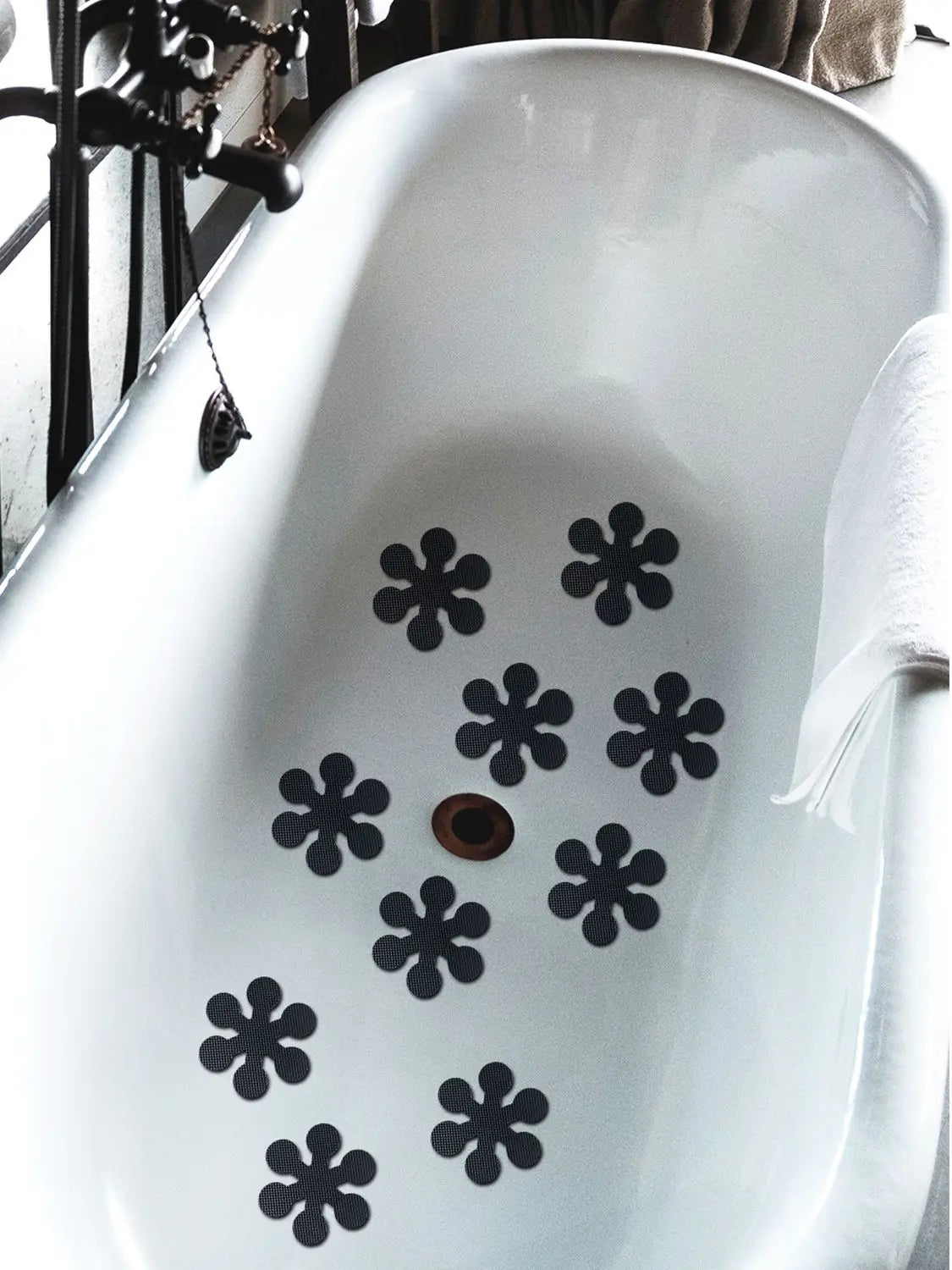Black snowflake anti-slip stickers placed on a white ceramic bathroom sink.