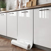 White marble peel-and-stick wallpaper film rolled out on a kitchen cabinet surface