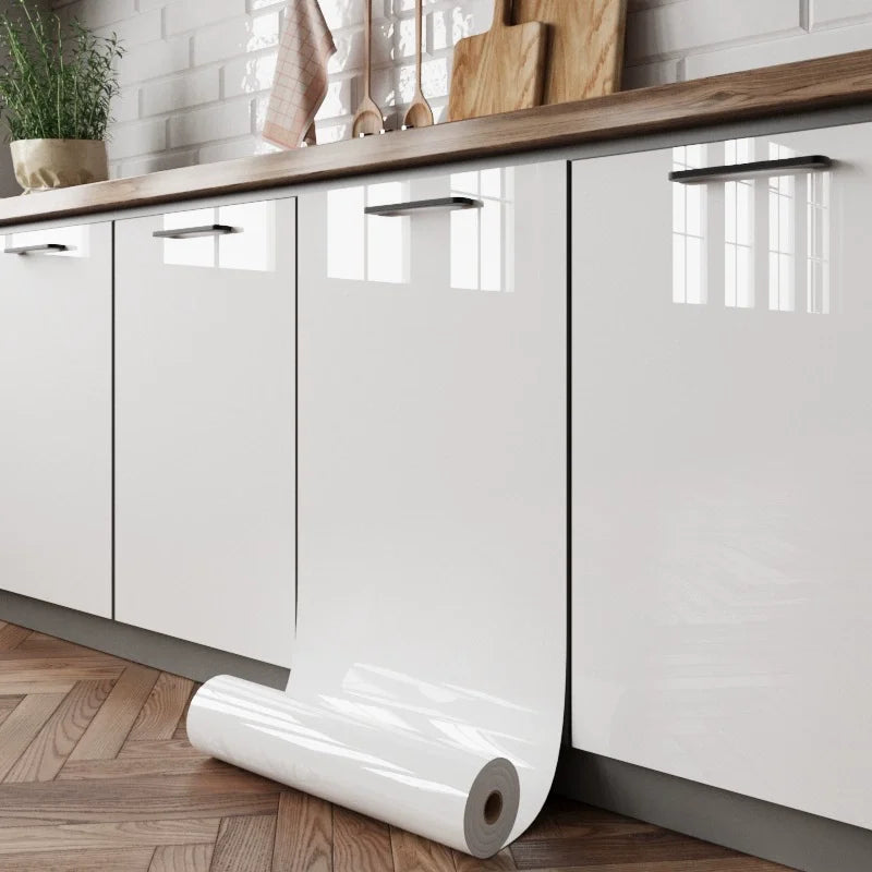 White marble peel-and-stick wallpaper film rolled out on a kitchen cabinet surface