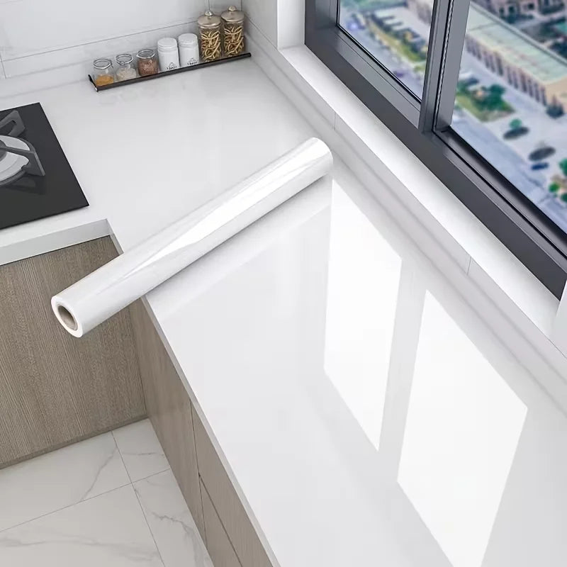 A roll of pearl finish waterproof self-adhesive wallpaper displayed on a white countertop near a window.