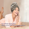 A woman is using a microfiber hair drying towel while talking on a phone.