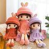 A set of three soft and cuddly plush dolls shaped like rabbits in shades of pink, purple, and orange.