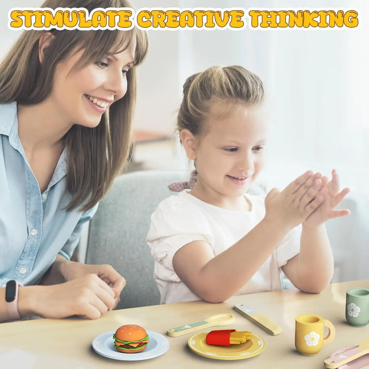 A woman and a girl are shown in a bright room with a wooden cookie play food set and baking accessories on a table.