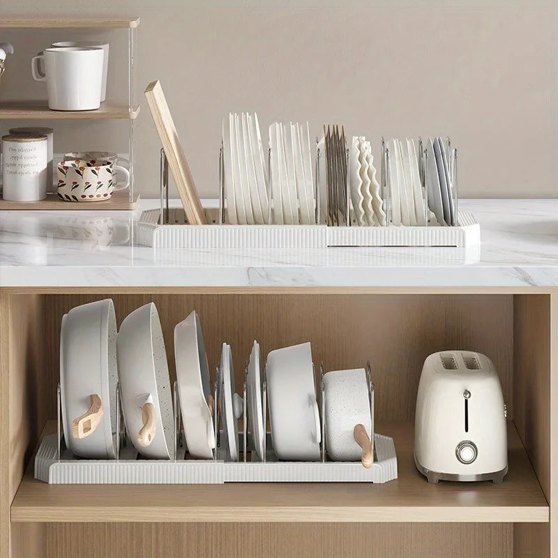 A white expandable pot and pan organizer rack with adjustable dividers is displayed on a wooden shelf.