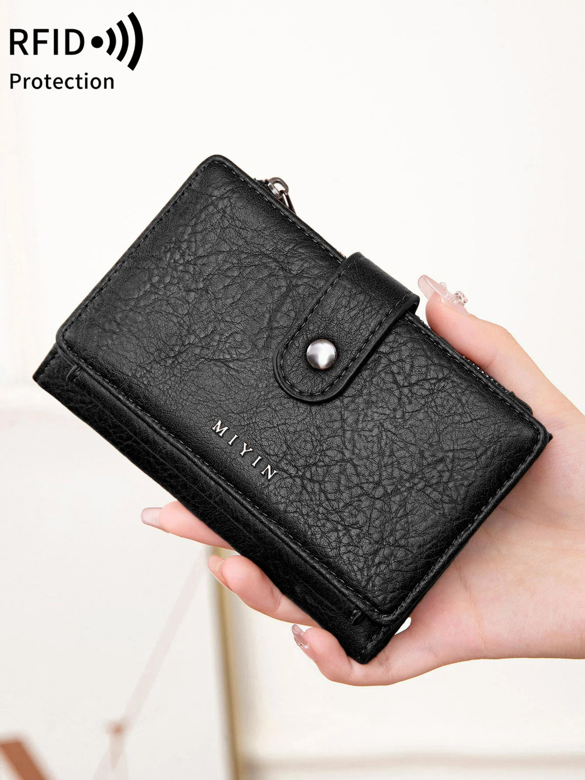 Une main tient un porte-monnaie portefeuille bi-pli en cuir noir bloqueur RFID.
