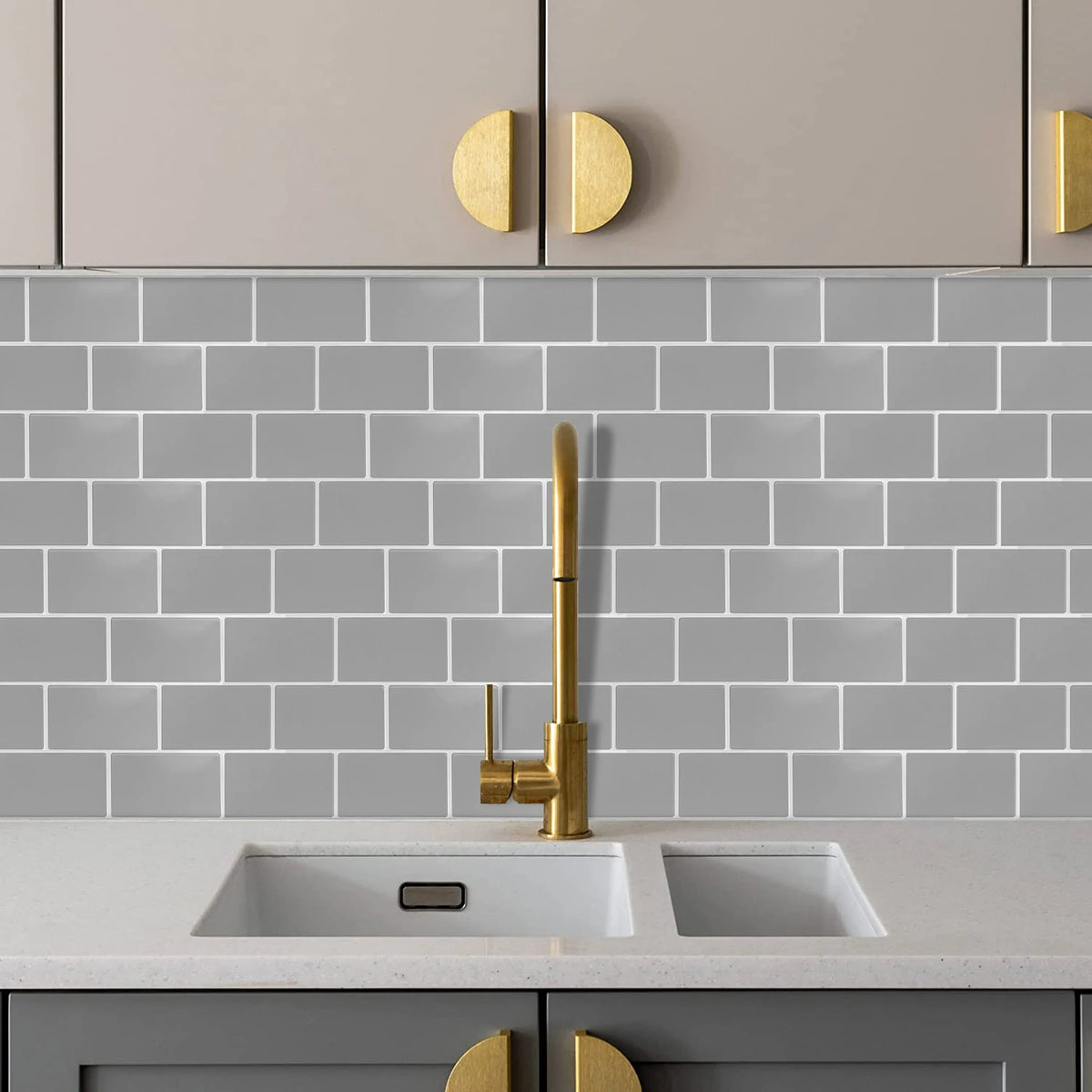 A kitchen countertop with a white sink and faucet set against a gray subway tile backsplash and light gray cabinetry.