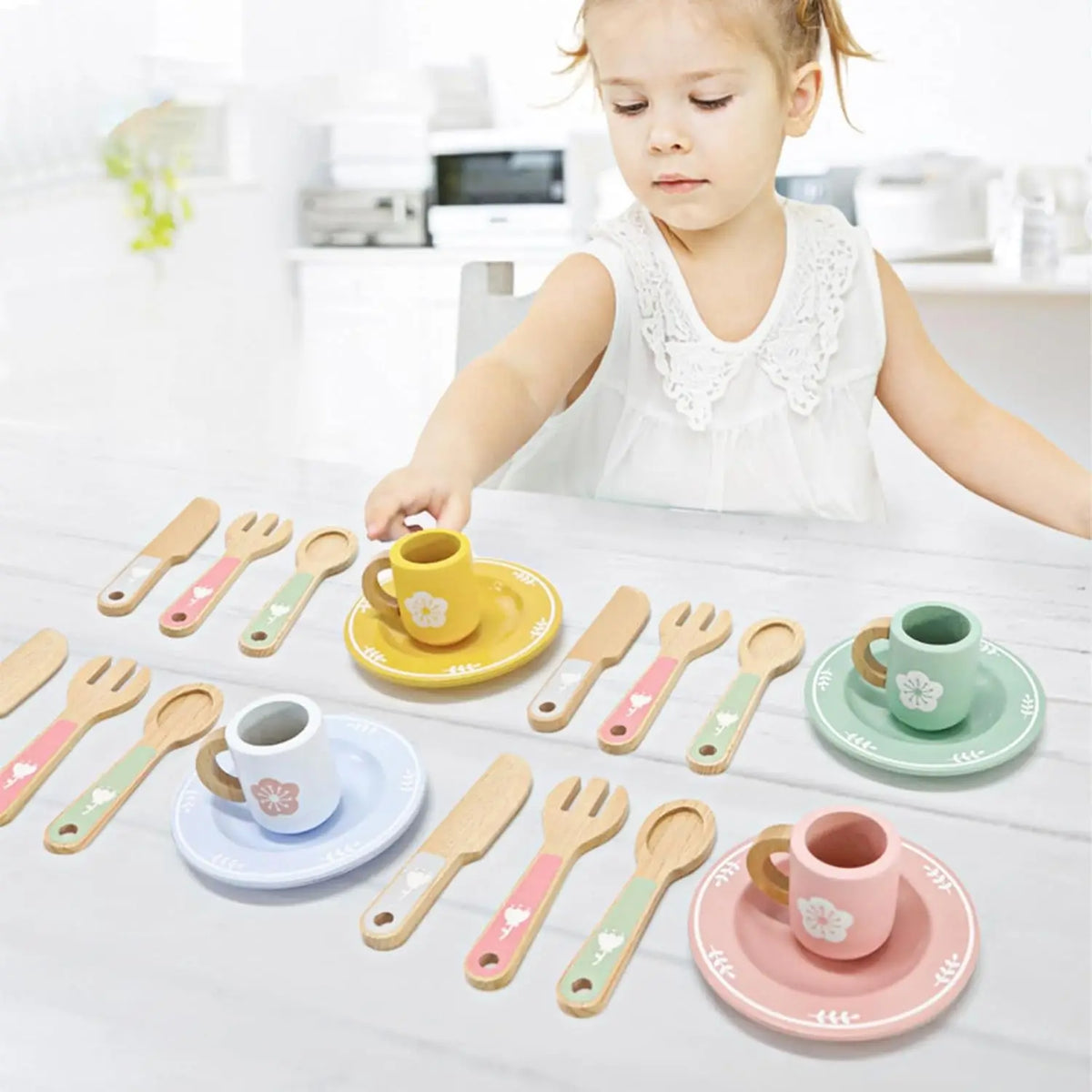 A set of wooden cookie play food and baking accessories with various sized spoons and cups on a white surface.