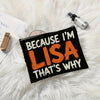 A black canvas makeup bag with orange text that reads Because I'm Lisa That's why resting on a white fluffy surface.