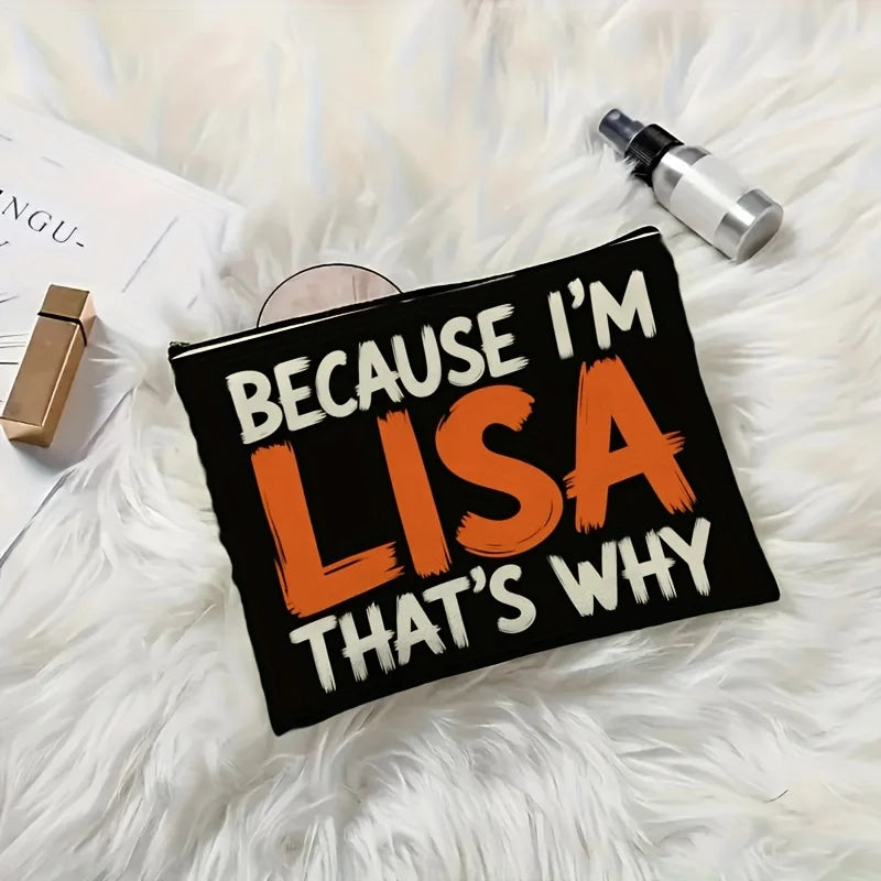A black canvas makeup bag with orange text that reads Because I'm Lisa That's why resting on a white fluffy surface.