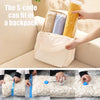 A hand is placing a yellow vacuum storage bag into a light-colored backpack, demonstrating the product's compact size.