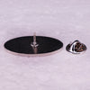 A silver enamel pin featuring an oval design with a small pin mechanism.