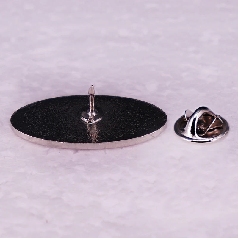 A silver enamel pin featuring an oval design with a small pin mechanism.