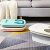 Two collapsible foot spa buckets in mint green and pink resting on a gray patterned rug.