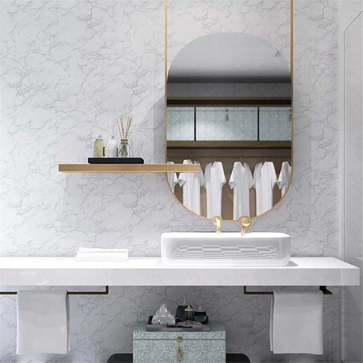 A bathroom vanity featuring a round mirror, gold accents, and a white sink on a marble-textured wall.