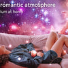 A woman relaxing on a couch looking up at a vibrant galaxy and star field projected onto the room.