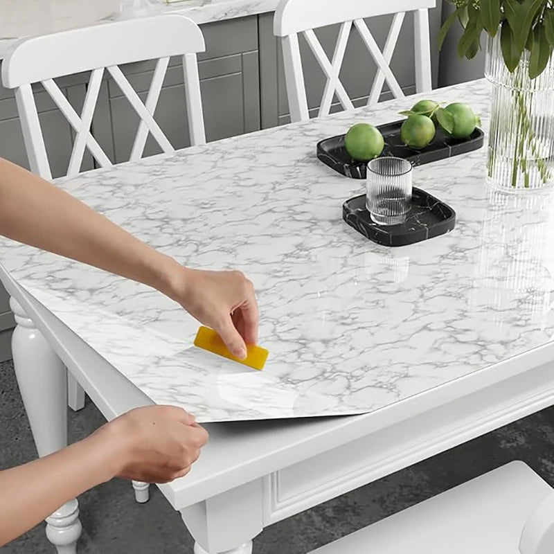 A hand is applying pearl finish waterproof self-adhesive wallpaper to a white marble tabletop.