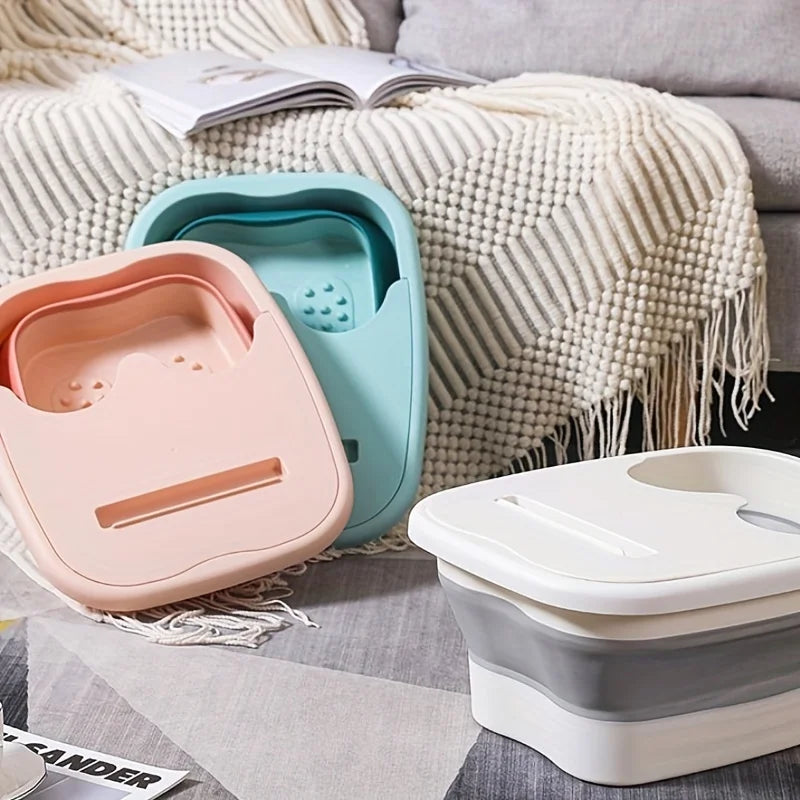 A pink and teal collapsible foot spa bucket is shown resting on a textured blanket next to a white container.
