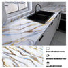 A black kitchen sink installed in a white countertop featuring marble pattern with gold veining.