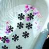 Pink and purple snowflake stickers floating on a white shower surface.