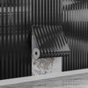 A close-up of a black self-adhesive wood grain grille wall sticker mounted on a light gray surface.