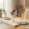 Kristallrosenblumen-Figurarrangement in einer Glasvase auf einem Holztable.