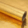 Roll of self-adhesive aluminum foil kitchen wall stickers lying on a reflective gold surface