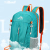 A teal ultra-light foldable travel backpack with orange straps and a white cloud design.