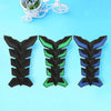 Three motorcycle tank pad protectors in black, green, and blue fish bone designs displayed on a light blue background.
