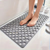 A gray anti-slip shower mat with massage points and drainage holes placed on a white surface.