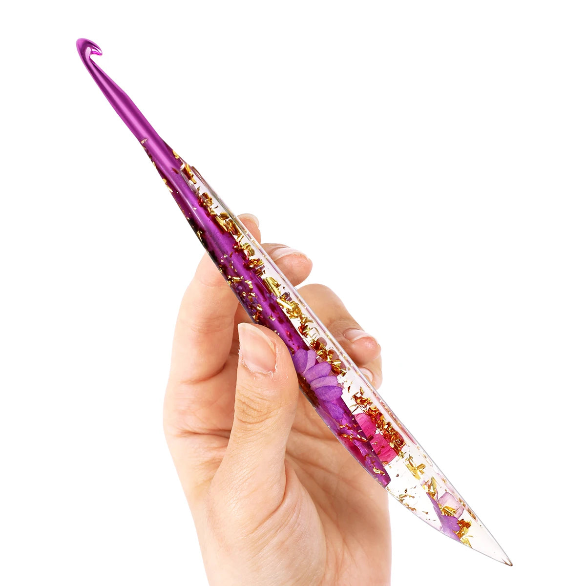 A hand holds a purple epoxy resin floral-patterned crochet hook set against a white background.
