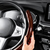 A hand installs a glossy carbon fiber clip-on steering wheel cover onto a car steering wheel.