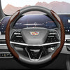 A close-up view of a steering wheel with an orange and black patterned leather cover in a modern car interior.