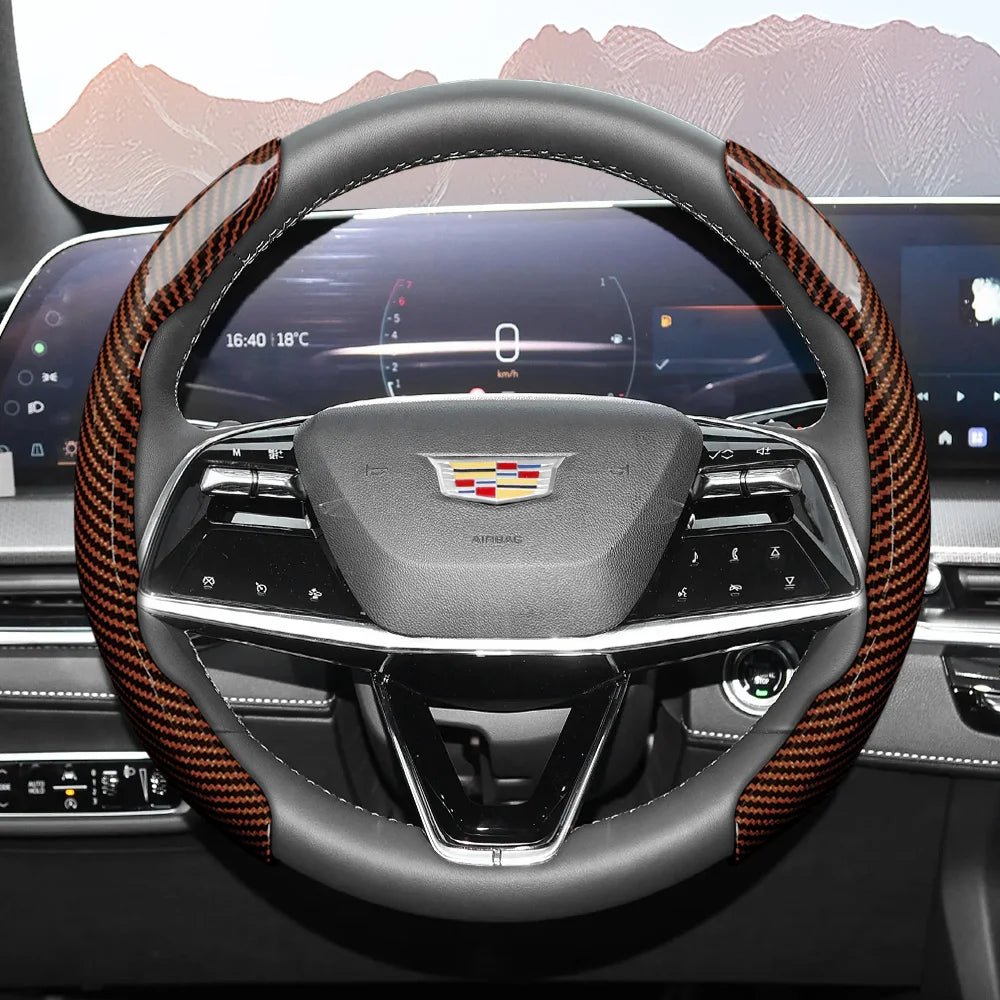 A close-up view of a steering wheel with an orange and black patterned leather cover in a modern car interior.