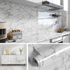 Close-up view of marble peel-and-stick wallpaper film being applied to a wall surface.