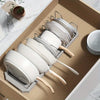 A wooden organizer rack holds several white ceramic pots and pans with adjustable dividers.