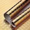 Roll of gold patterned aluminum foil kitchen wall stickers shown diagonally on a textured surface
